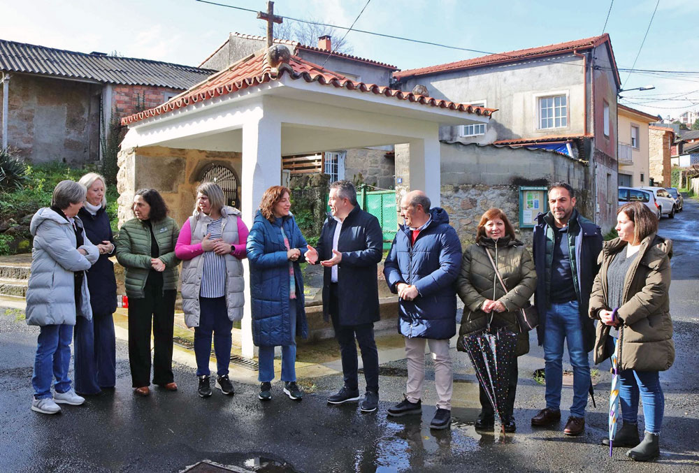 Grupo, encabezado pola conselleira e alcalde, visitando a fonte-lavadoiro